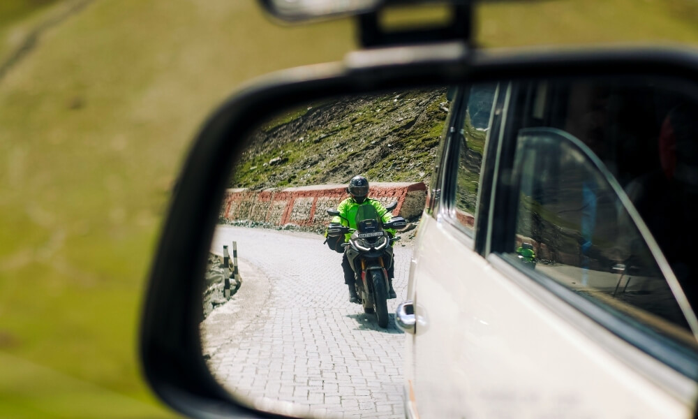 motocyklista w lusterku auta